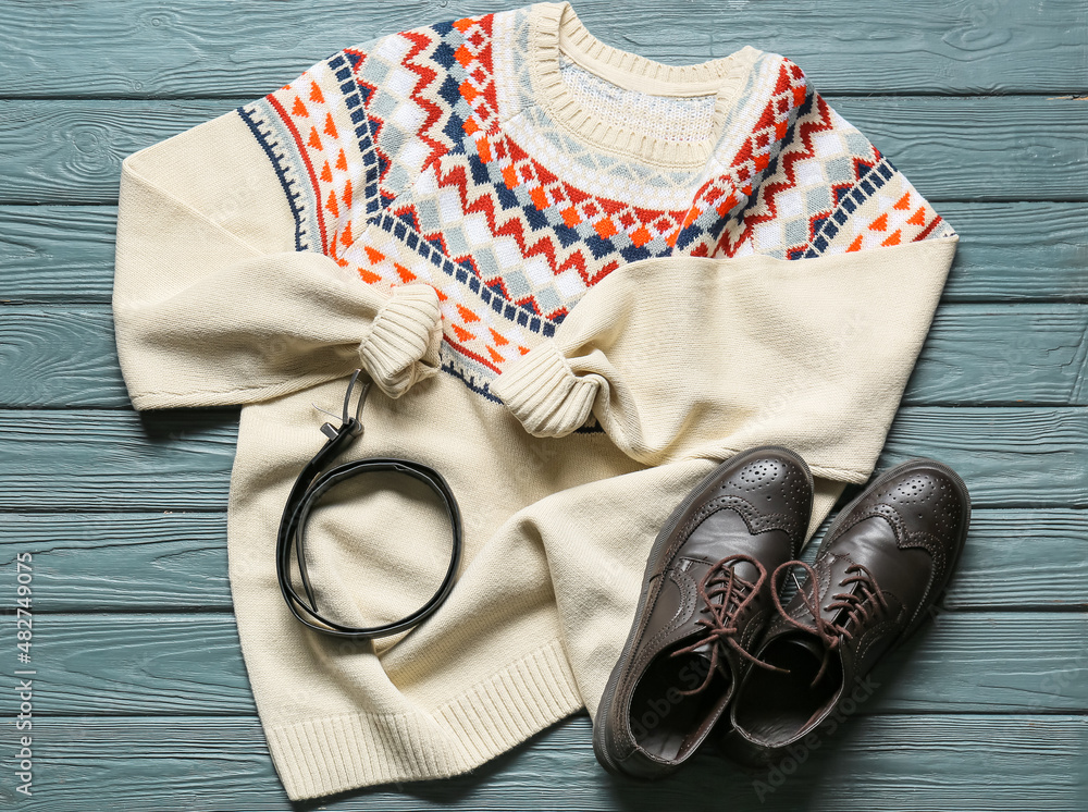 Male sweater, shoes and belt on color wooden background