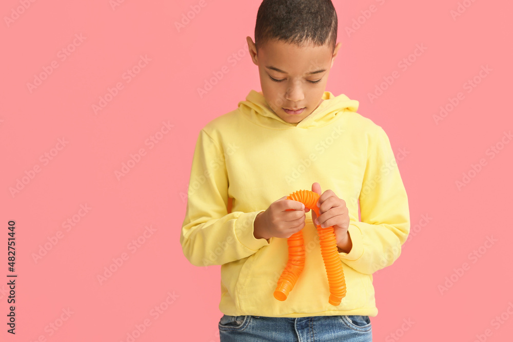 粉色背景下带橙色Pop Tube的非裔美国小男孩