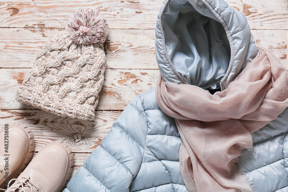 浅色木质背景的冬季夹克、围巾、帽子和鞋子