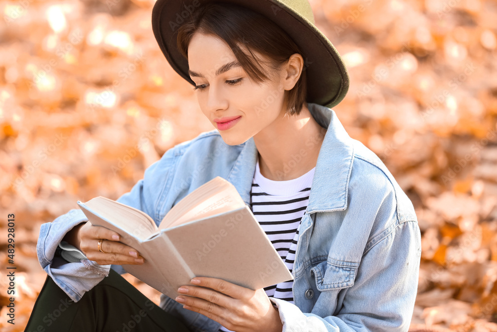 Beautiful woman reading interesting book in autumn park