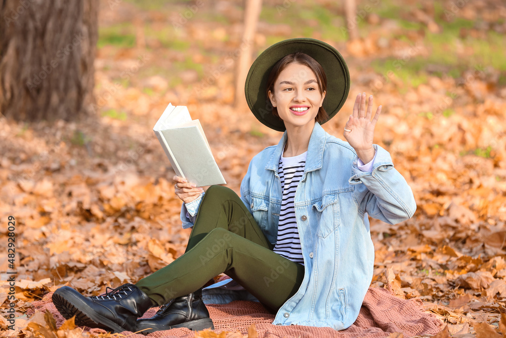 秋天公园里带着格子书的微笑女人