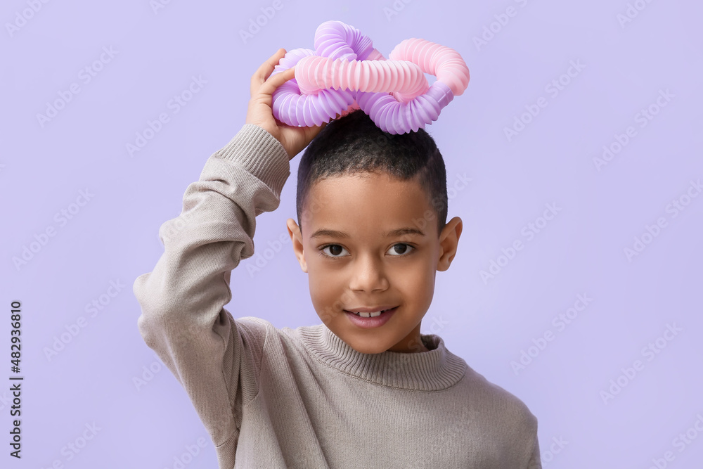 一个非洲裔美国小男孩，淡紫色背景下有粉色的Pop Tube