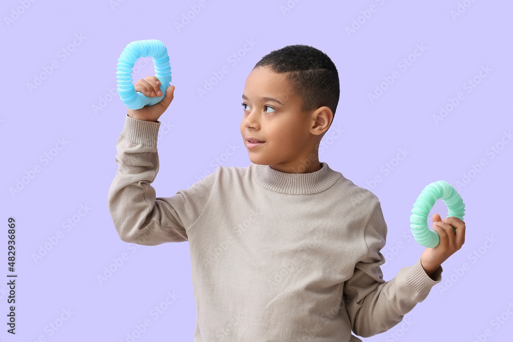 Little African-American boy with Pop Tubes on lilac background