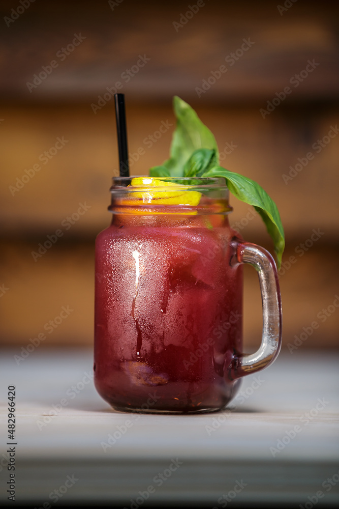 Fresh pomegranate lemonade with crushed ice and mint and straw on table with wood background