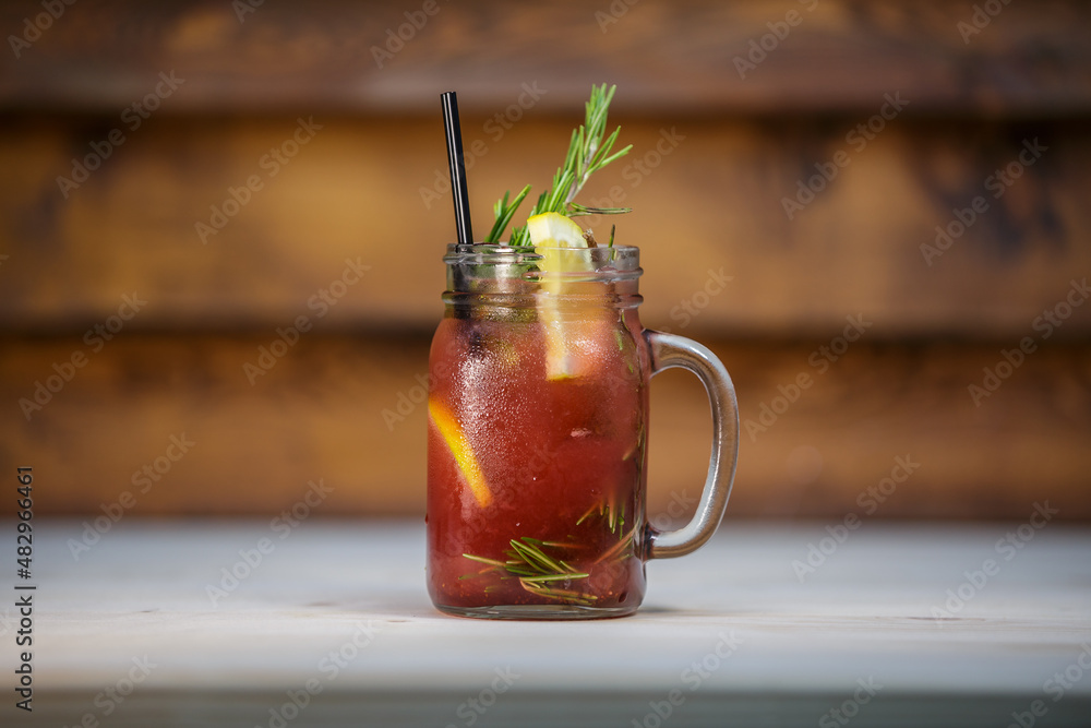 Fresh strawberry and pine lemonade with crushed ice and mint and straw on table with wood background