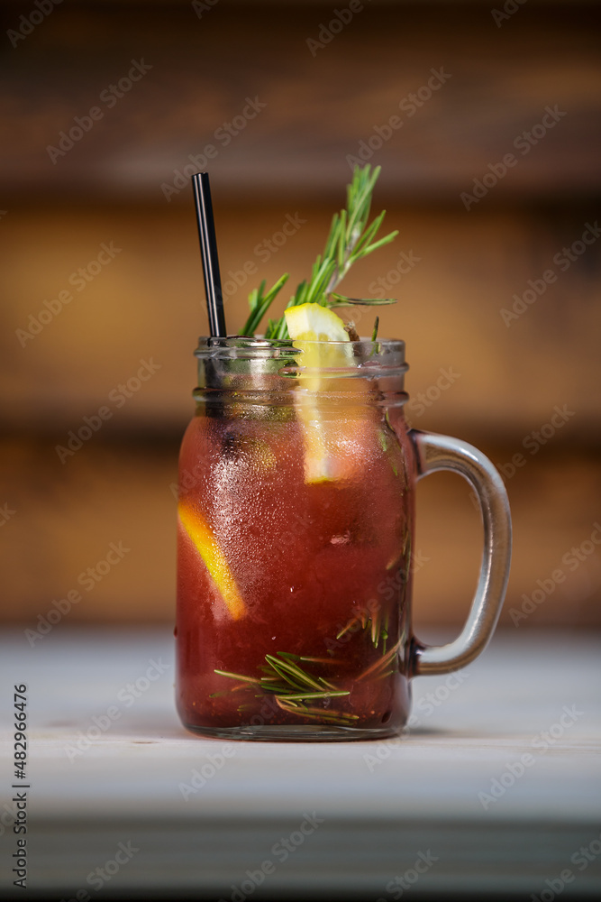 Fresh strawberry and pine lemonade with crushed ice and mint and straw on table with wood background