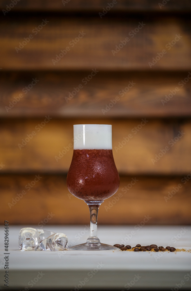 Crushed ice coffee with cinamon in brandy glass on table with wood background and coffee beans