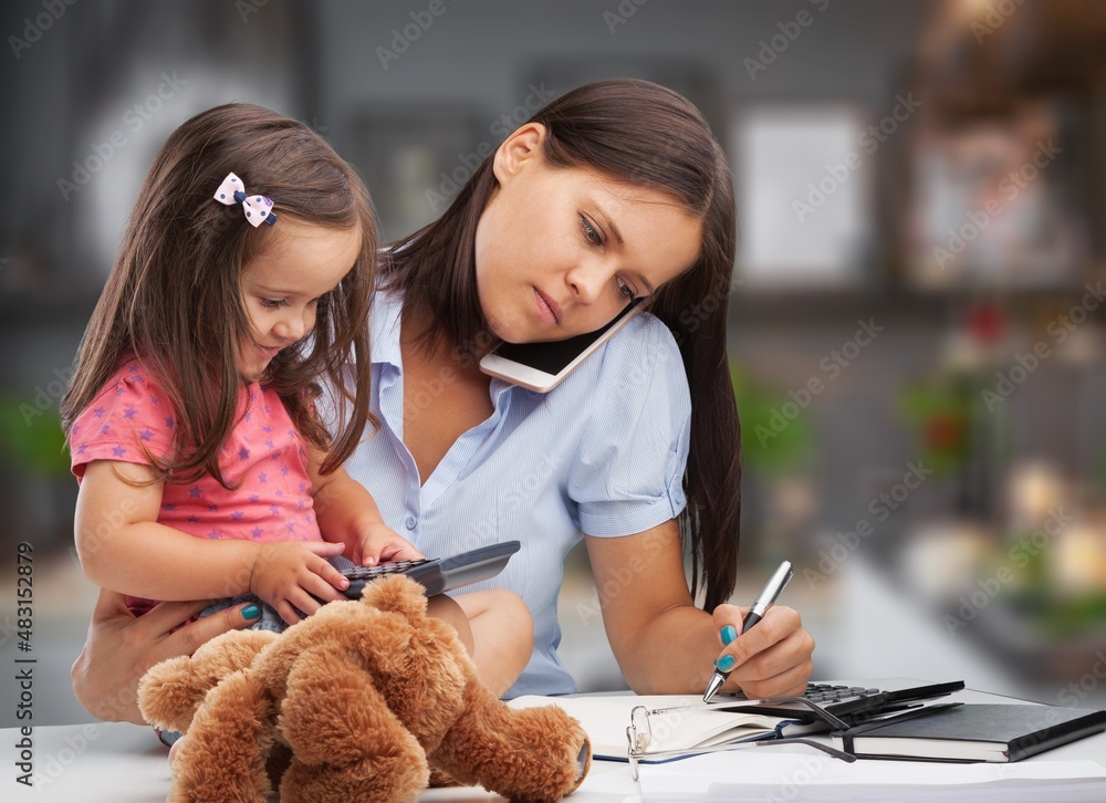 Beautiful young mother working at home with little spoiled child . Mom or teacher and little girl ch