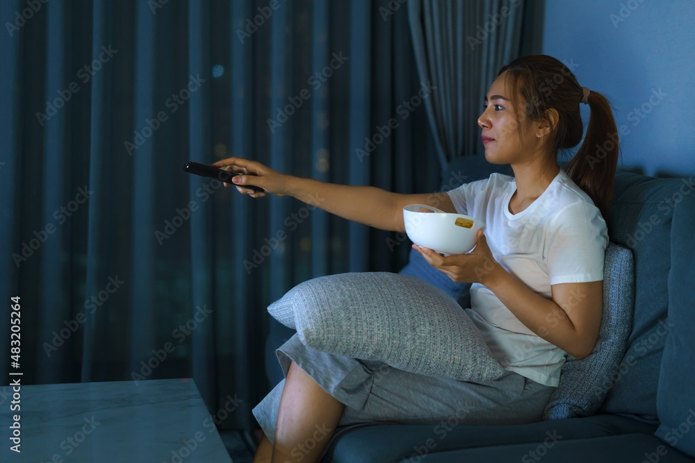 asian woman watching television suspense movie or news looking happy and funny and eating popcorn la