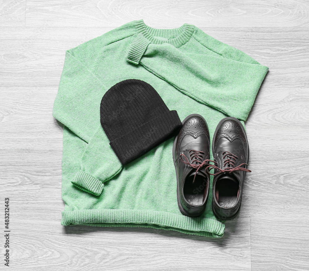 Male sweater, hat and leather shoes on light wooden background