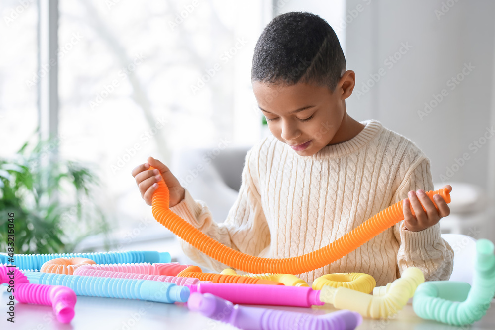 可爱的非裔美国小男孩在家玩橙色Pop Tube