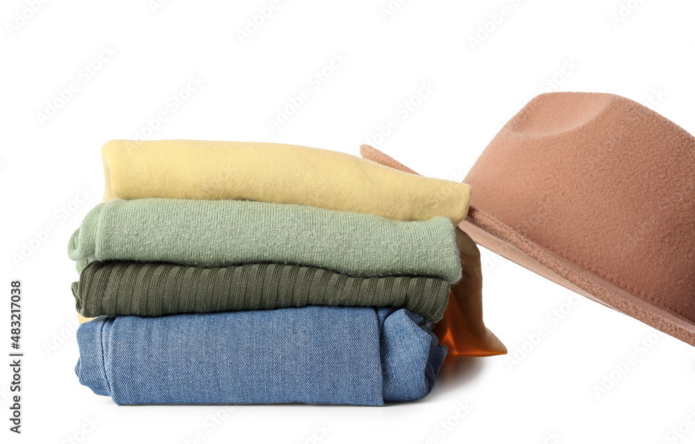 Stack of different stylish clothes and felt hat on white background, closeup
