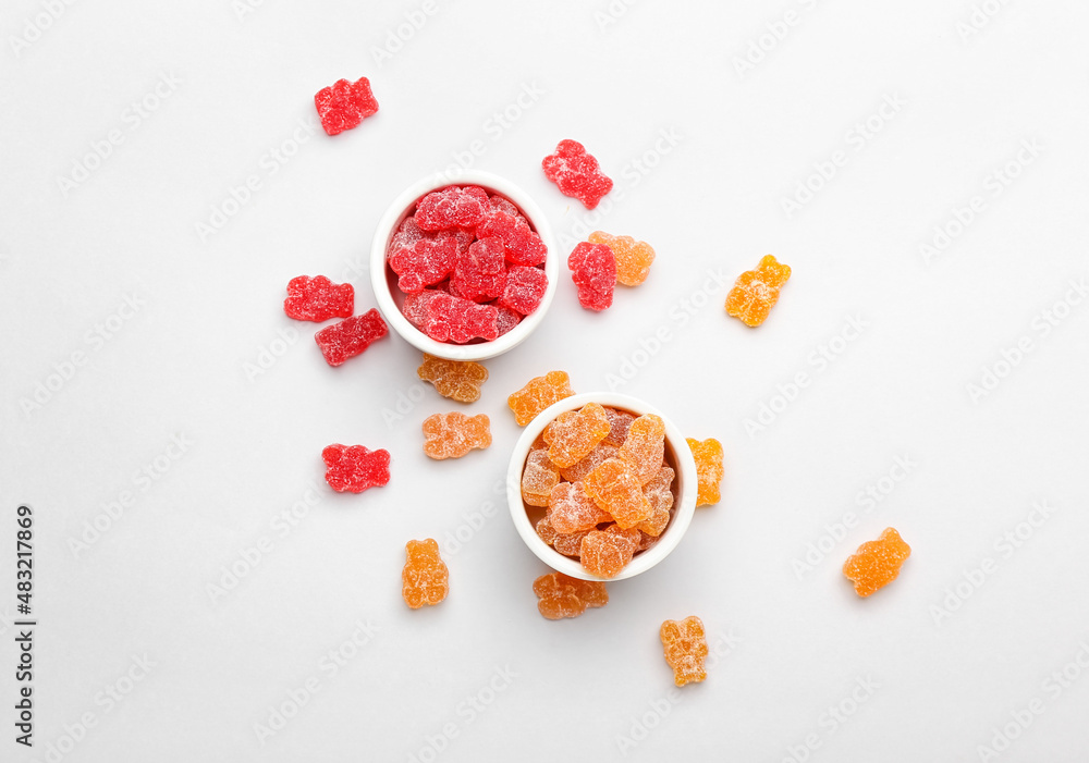 Bowls with tasty jelly bears on white background