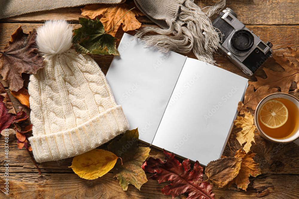 空白书、一杯茶、相机和木制背景的秋季装饰