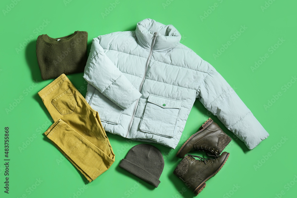 绿色背景的冬季夹克、毛衣、裤子、帽子和鞋子