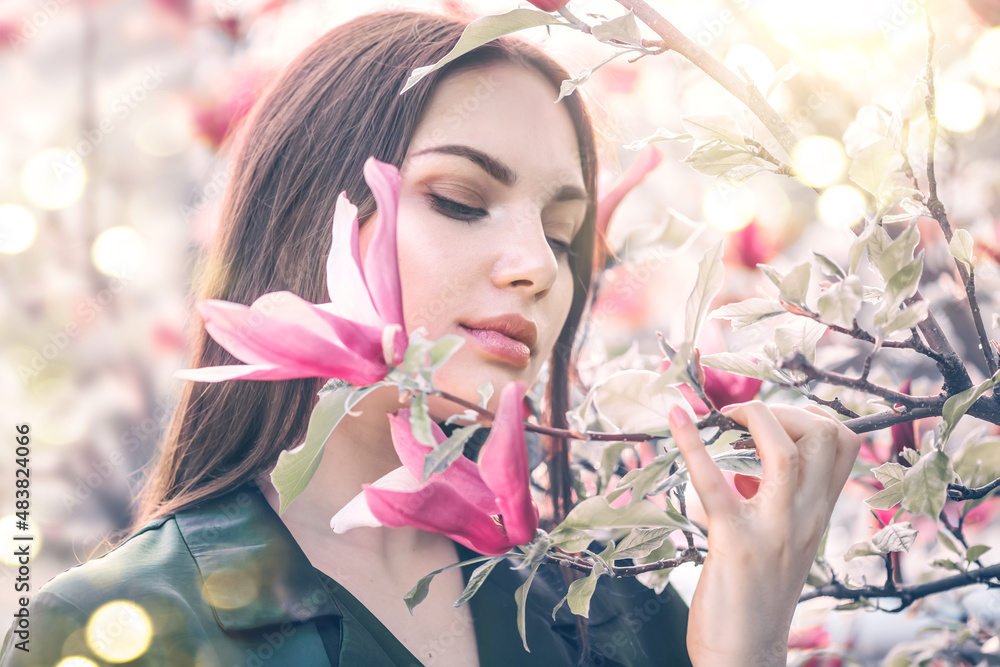Beauty young woman enjoying nature in spring spring magnolia flowers. Beautiful brunette girl in Gar