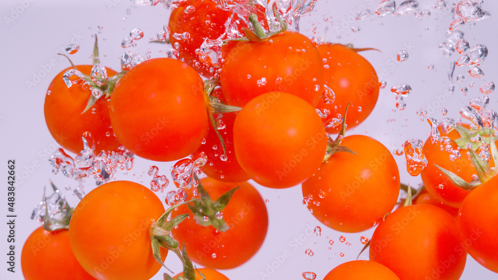 UNDERWATER: Small red tomatoes falling and splashing into the cold fresh water