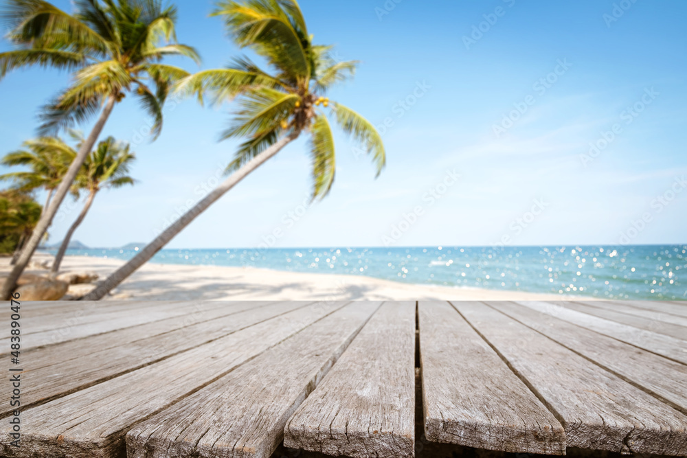 木质桌子顶部有海景和棕榈树，热带海滩上平静的大海和天空的光线模糊