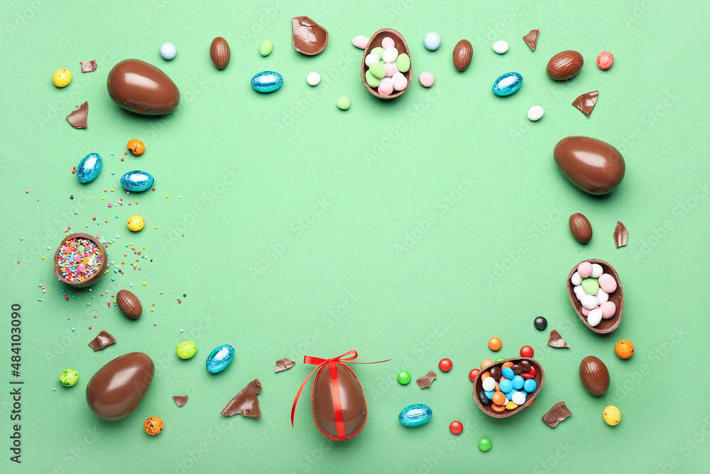 由巧克力复活节彩蛋、糖果和绿色背景上的点缀制成的框架