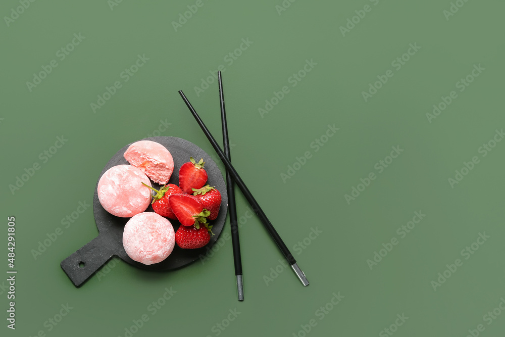 彩色背景上有美味的糯米团、草莓和筷子的木板