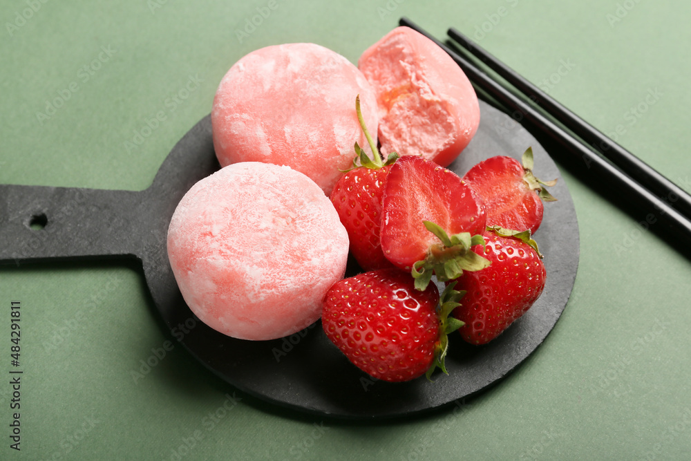 Board with delicious mochi, strawberry and chopsticks on color background