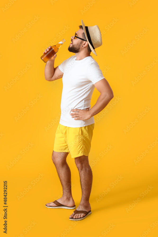 戴墨镜的年轻人在黄色背景下喝啤酒
