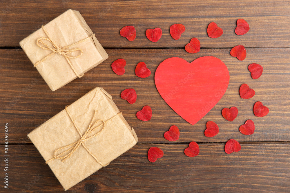 情人节问候概念。木制十字架上的红色木制小爱心和礼品盒