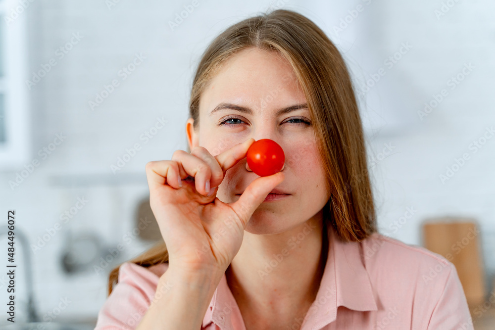 顽皮的美女拿着西红柿摆姿势。素食主义者的食物情感画像。
