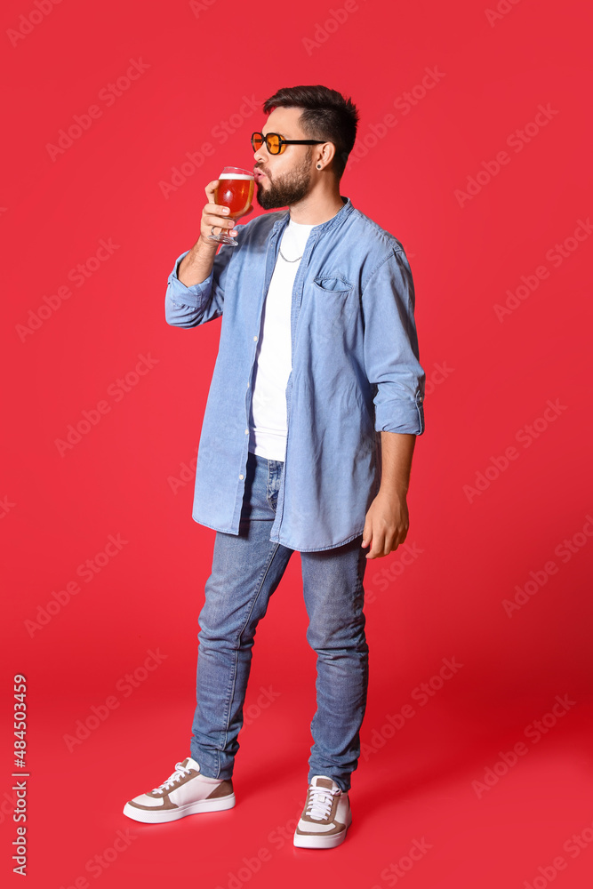戴墨镜的英俊男子在红底喝啤酒