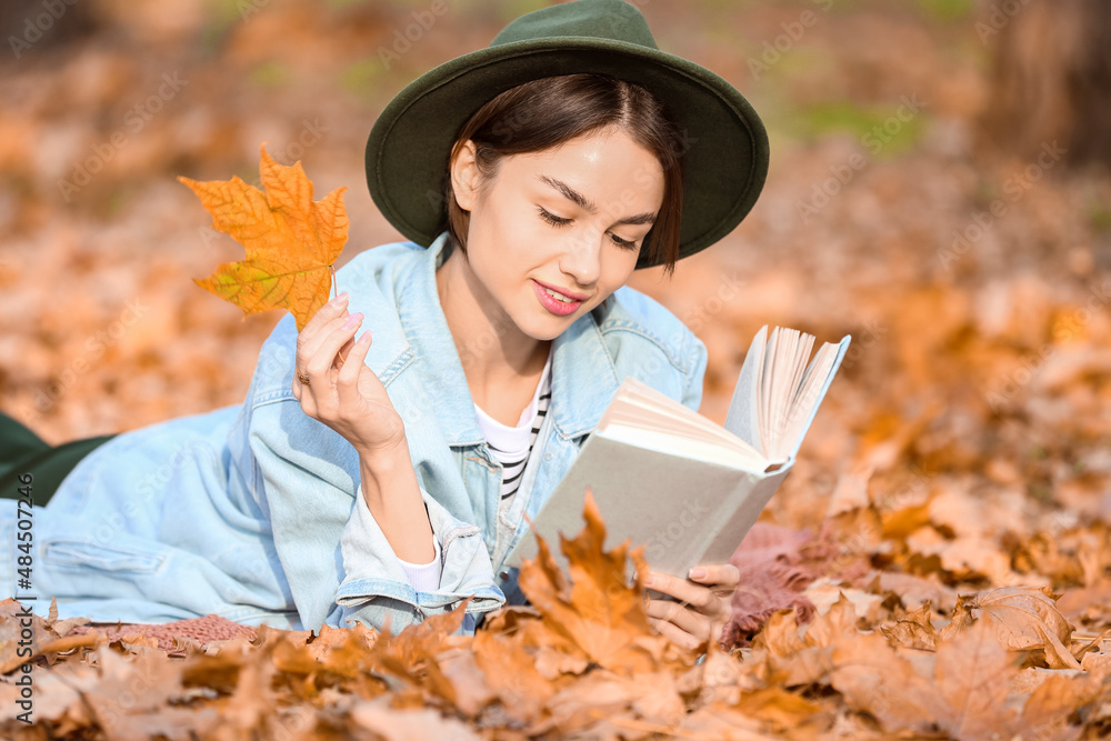 公园里拿着秋叶看书的美女画像