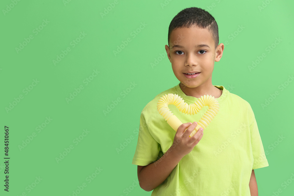 Little African-American boy with yellow Pop Tube on green background