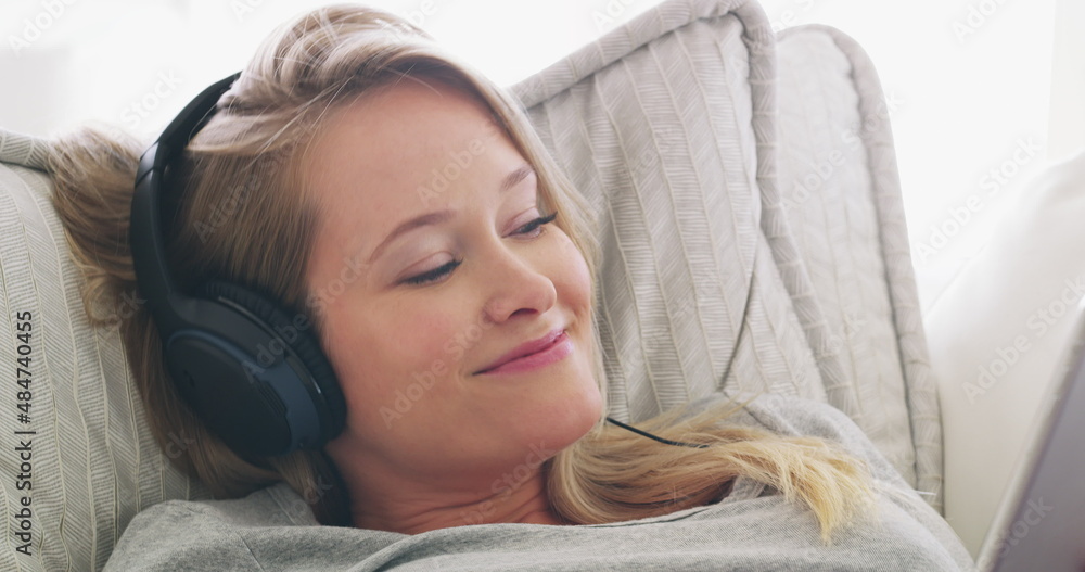 音乐有治愈的能力。一个女人在沙发上放松时听音乐的4k视频。