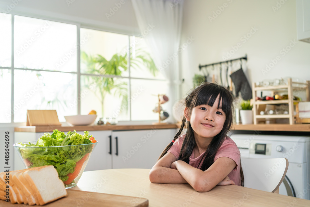 亚洲小孩微笑着看着厨房里的相机的肖像。