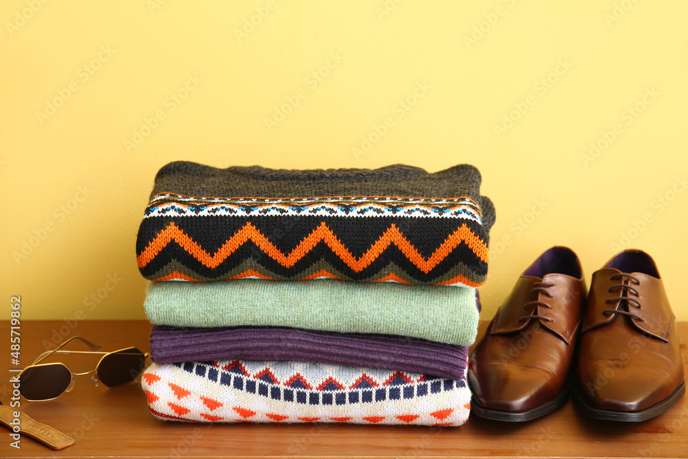 彩色墙附近的桌子上放着一堆时尚的毛衣、配饰和鞋子