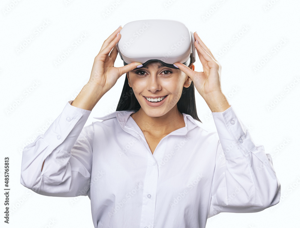虚拟现实概念：面带微笑的年轻女子，穿着浅色衬衫，头上戴着VR耳机，隔离在墙上