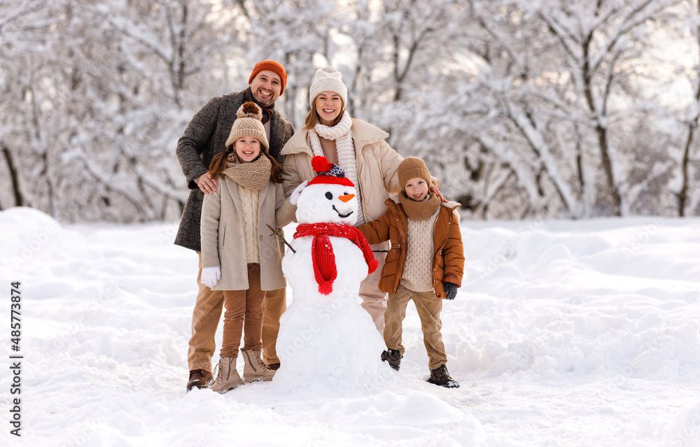 快乐的一家人穿着暖和的衣服，一起堆雪人，开心地笑着