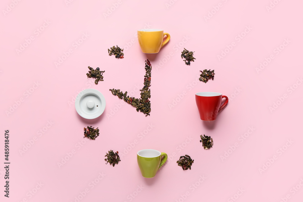 粉红色背景的杯子和干茶叶制成的时钟