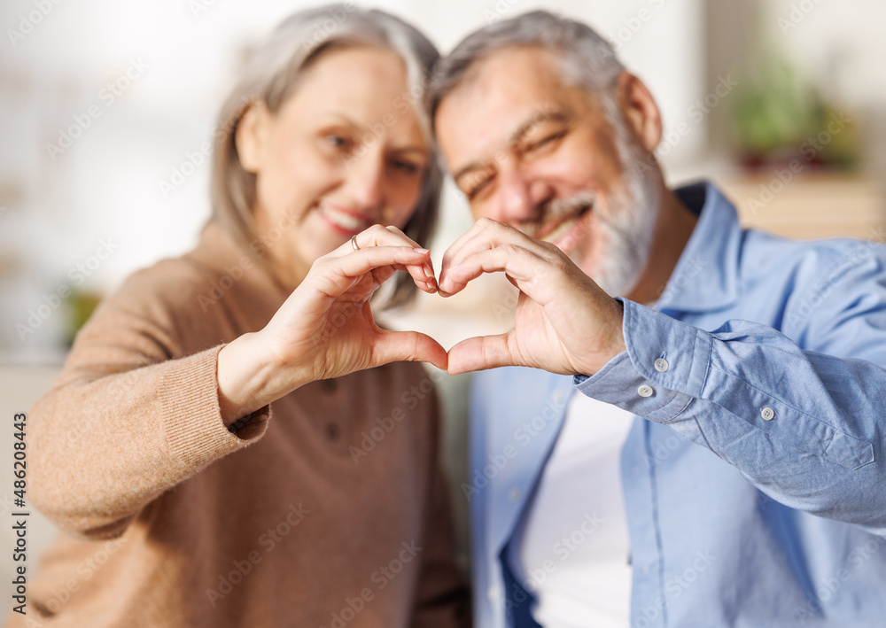 Valentines Day for Seniors. Happy elderly family couple in love make heart sign with hands