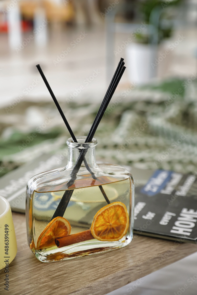 Aroma reed diffuser with magazine on table in room