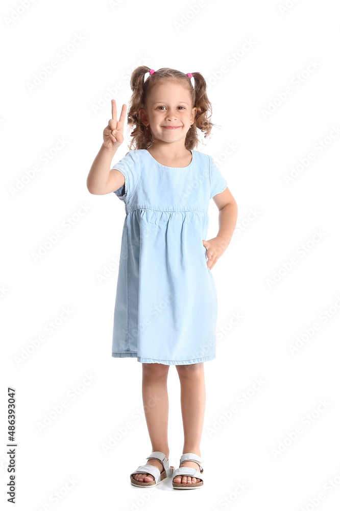 穿着蓝色连衣裙的有趣小女孩在白底上展示胜利手势