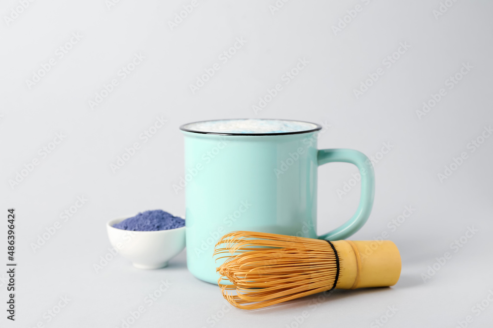 Cup of blue matcha latte, chasen and bowl with powder isolated on white background
