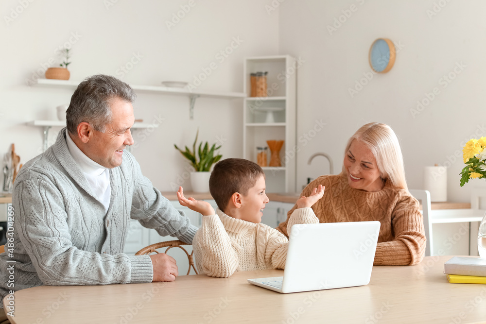 穿着保暖毛衣的小男孩和爷爷奶奶在家视频聊天