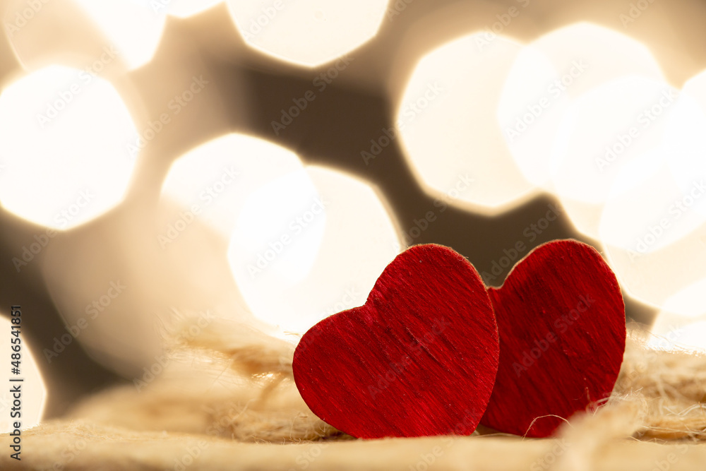 Valentines Day greetings concept. Little red wooden heart close up, party lights bokeh on backgroun