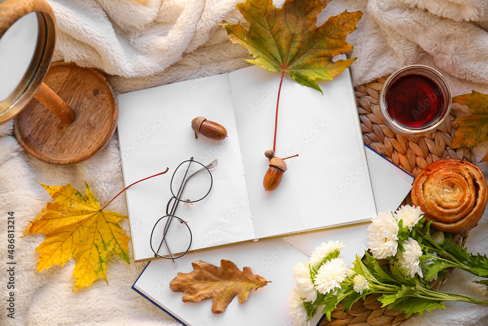 格子布上的书籍、眼镜、一杯茶和秋季装饰
