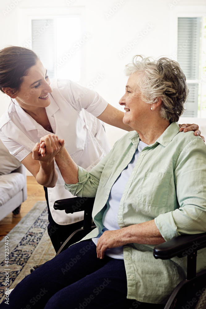 她和病人相处得很好。一位微笑的护理者帮助一位坐在轮椅上的老年妇女的照片