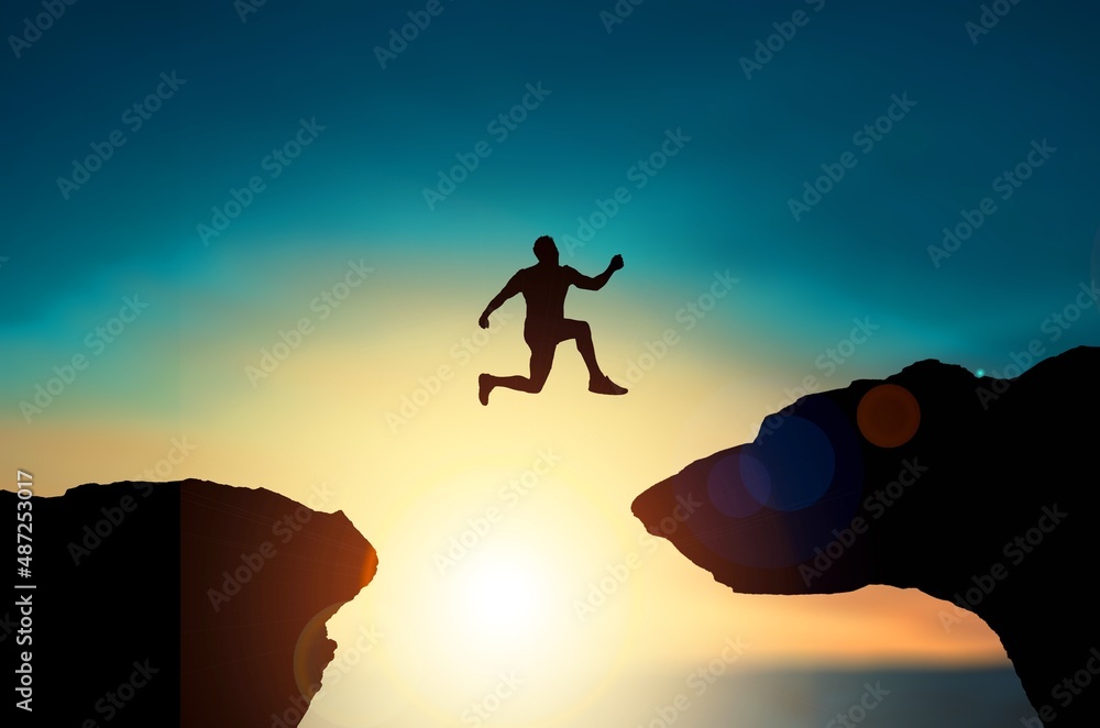 在2021至2022年间，以日落为背景的剪影男子跳跃，成功的新年概念。