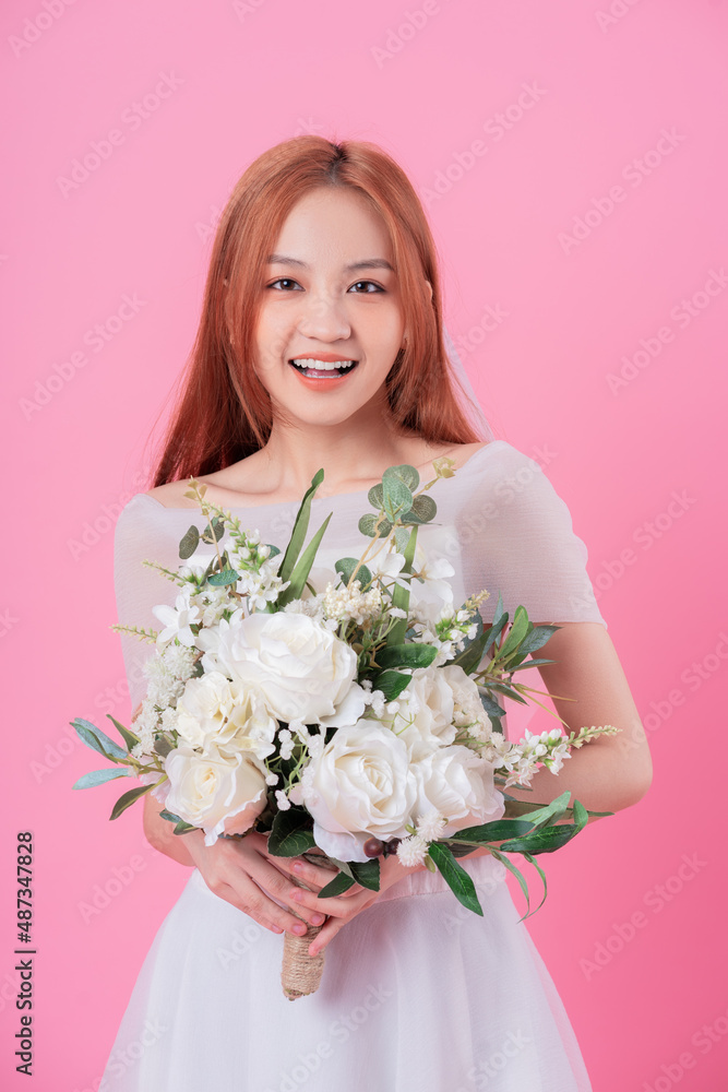 年轻的亚洲新娘在粉色背景下摆造型