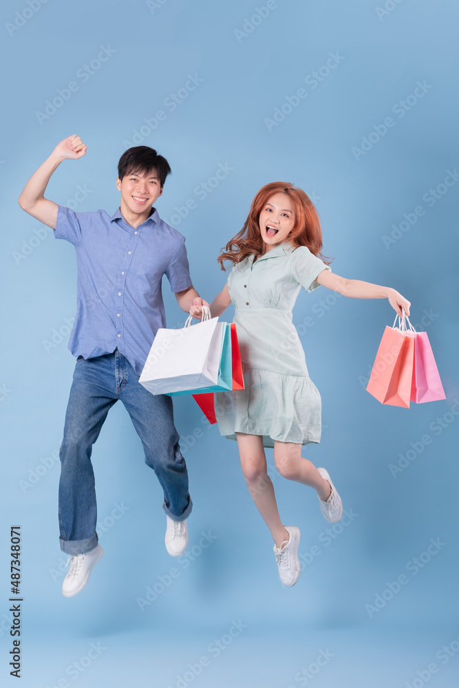 亚洲年轻夫妇背着蓝色背景的购物袋