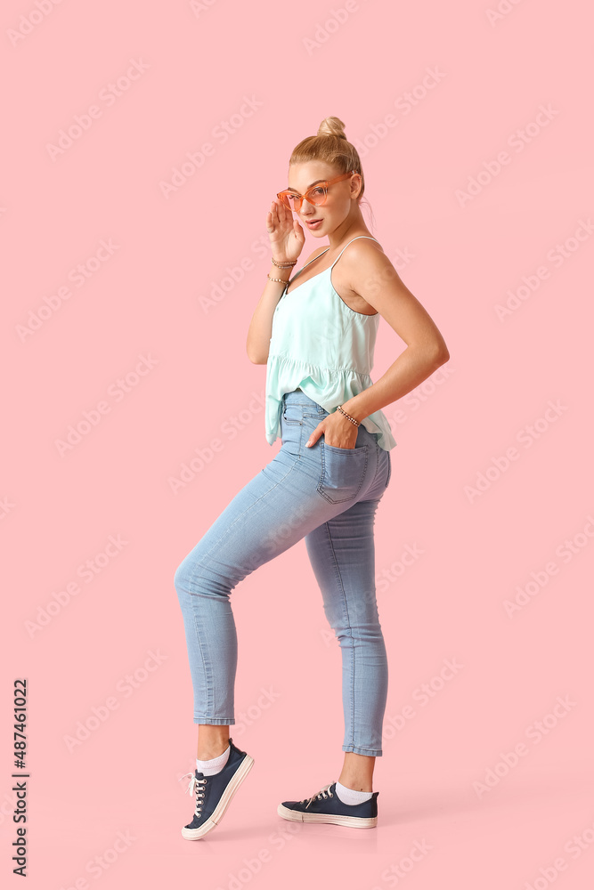 时尚的年轻女人穿着时尚的牛仔裤在彩色背景