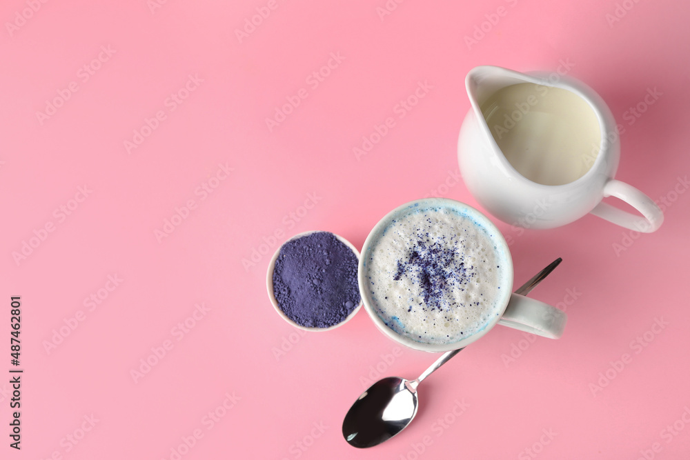 一杯蓝色抹茶拿铁，粉红色背景的粉末和牛奶